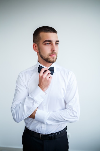 Il giovane uomo d'affari maschio vestito con una camicia bianca con una barba corta indossa un papillon nero