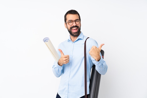 Il giovane uomo dell'architetto con la barba sopra bianco isolato con i pollici aumenta il gesto e sorridere