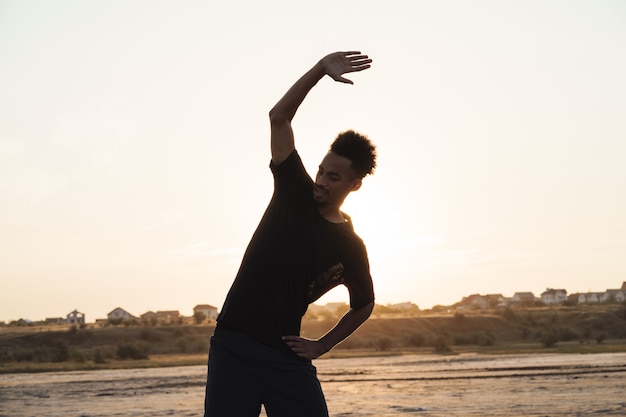 Il giovane uomo di sport fa esercizi di fitness all'aperto