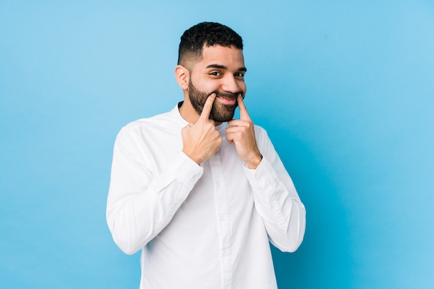 Il giovane uomo latino contro una parete blu ha isolato il dubbio fra due opzioni.