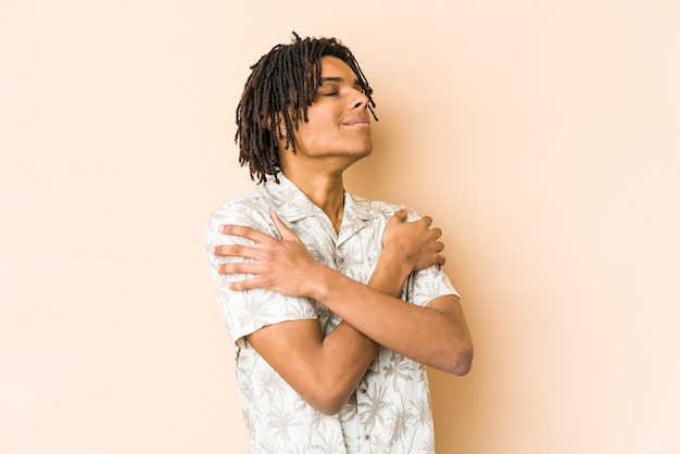 Il giovane uomo rasta afroamericano abbraccia, sorridente spensierato e felice.