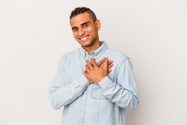 Il giovane venezuelano isolato sul muro bianco ha un'espressione amichevole, premendo il palmo sul petto. Concetto di amore.