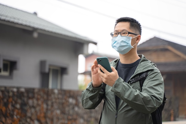 Il giovane zaino in spalla viaggia da solo e usa lo smartphone per trovare un modo con maschera e occhiali