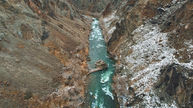 Il Grand Canyon nella steppa con il fiume color smeraldo. Una crepa nel terreno con pietre nere