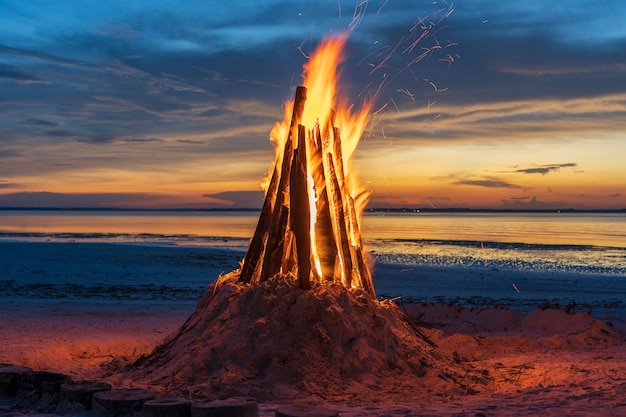 Il grande fuoco brucia sullo sfondo del cielo notturno vicino al mare sull'isola di Zanzibar, Tanzania, Africa orientale, primo piano. Fiamma brillante. Un falò la sera.