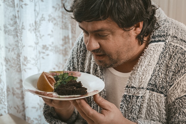 Il grande uomo tiene il piatto con alimento sano che lo osserva