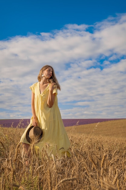 Il grano maturo del raccolto cresce nel campo il grano dorato e la ragazza sta camminando attraverso il campo...