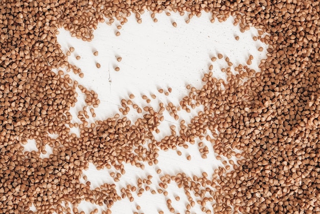 Il grano saraceno è sparso casualmente su uno sfondo bianco. Vista dall'alto. Copia, spazio vuoto per il testo
