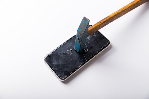 Il grosso martello con manico in legno rompe lo smartphone