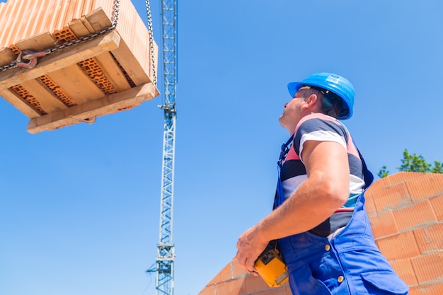 Il gruista consegna un pallet in mattoni in costruzione o in cantiere