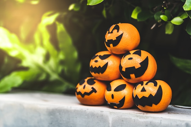 Il gruppo di arance affronta la pittura con spaventoso il giorno della festa di Halloween al posto del giardino.