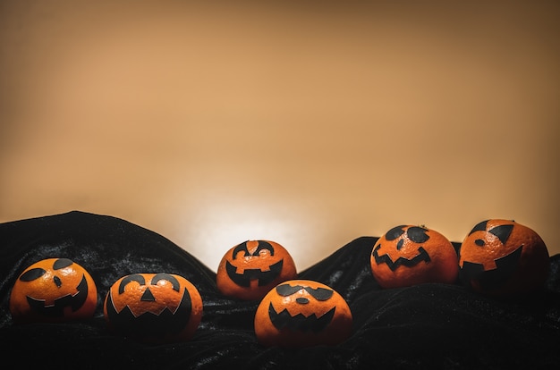 Il gruppo di arance affronta la pittura con spaventoso il giorno della festa di Halloween con fondo arancio.