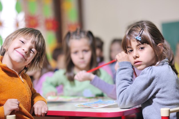 il gruppo di bambini felici si diverte e gioca al concetto di educazione prescolare al coperto dell'asilo con l'insegnante