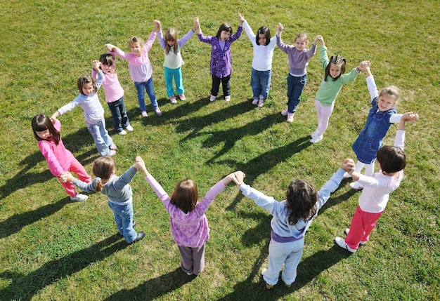 il gruppo di bambini felici si diverte e gioca al concetto di educazione prescolare all'aperto dell'asilo con l'insegnante