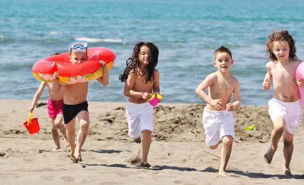 il gruppo di bambini felici si diverte sulla spiaggia mentre gioca con i giocattoli che corrono saltando