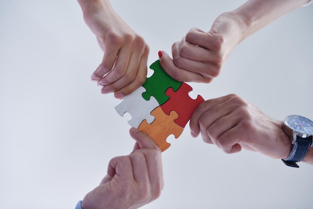 Il gruppo di gente di affari che monta il puzzle e rappresenta il supporto del gruppo e aiuta il concetto