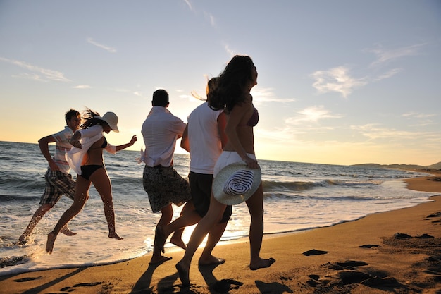 il gruppo di giovani felici si diverte a correre e saltare su beacz all'ora del tramonto