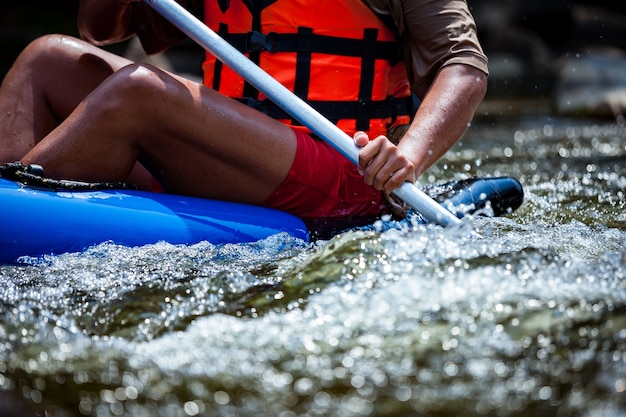 Il gruppo di giovani sta trasportando rafting in un fiume. Avvicinamento