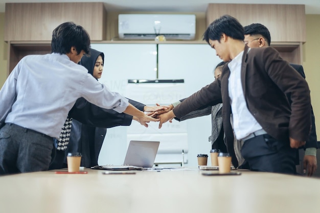 Il gruppo di lavoratori d'affari sta impilando le mani insieme sul tavolo dell'ufficio.