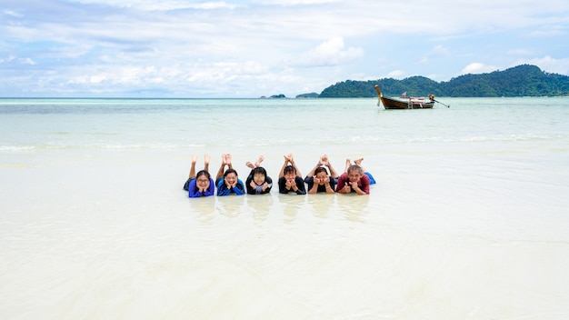 Il gruppo di persone asiatiche è una famiglia, la vita felice si gode sdraiandosi insieme sulla spiaggia dell'isola di Ra Wi durante le vacanze di viaggio in mare durante le vacanze estive a Ko Lipe, Tarutao, Satun, Thailandia, widescreen 16: 9