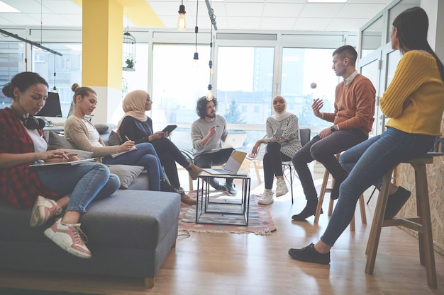 il gruppo di uomini d'affari in un ufficio moderno ha una riunione di squadra e un brainstorming mentre lavora su tablet o laptop presentando idee e prendendo appunti