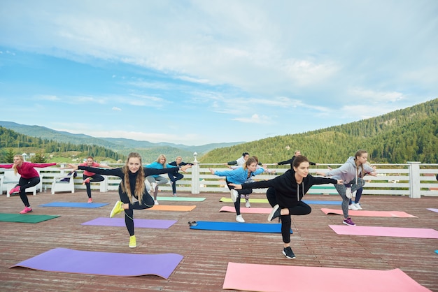 Il gruppo di yoga che fa gli esercizi di equilibrio su una gamba.