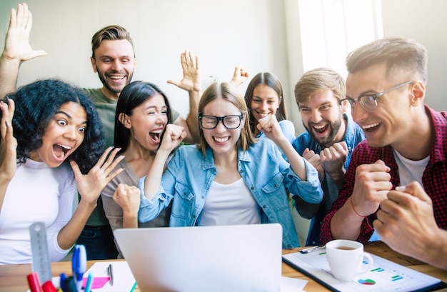 Il gruppo moderno felice e di successo del team di avvio aziendale sta guardando sul monitor del laptop dopo aver terminato il grande progetto. Studenti divertenti