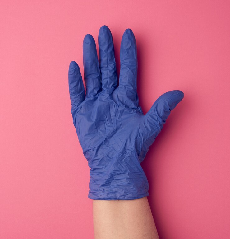Foto il guanto medico blu è indossato sul braccio, parte del corpo su uno sfondo rosa