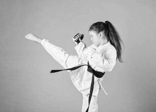 Il karate dà una sensazione di fiducia Bambino forte e sicuro di sé È pericolosa Bambina in kimono bianco con cintura Combattente di karate pronto a combattere Concetto di sport di karate Abilità di autodifesa