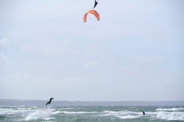 Il kitesurf cavalca le onde della tavola durante la tempesta che tiene l'aquilone volante