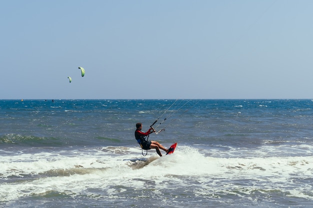 Il kitesurfer maschio si muove sulla scacchiera sulle onde del mare