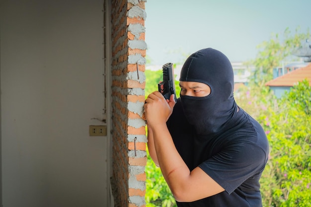 Il ladro con la pistola e lo sguardo mentre si trova vicino al muro