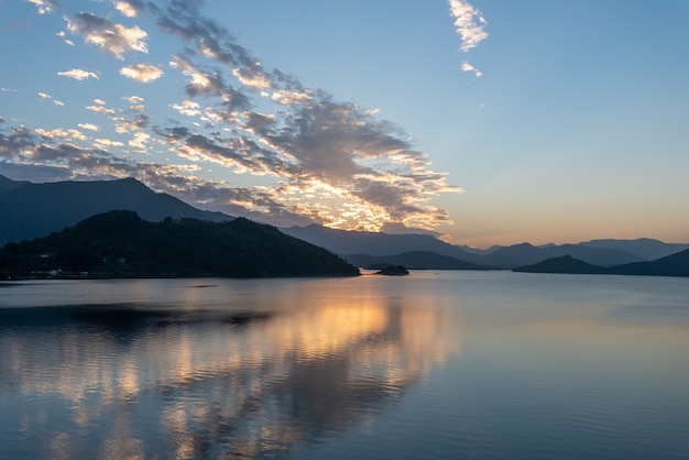 Il lago della sera rifletteva il bagliore del tramonto e le montagne