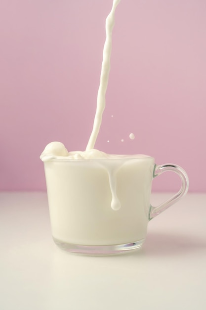 Il latte viene versato in una tazza trasparente su uno sfondo viola