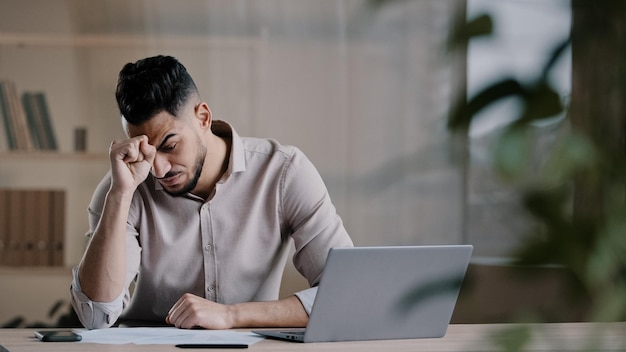 Il lavoratore arabo scioccato infelice guarda lo schermo del laptop sentendosi nervoso sconvolto dalle cattive notizie