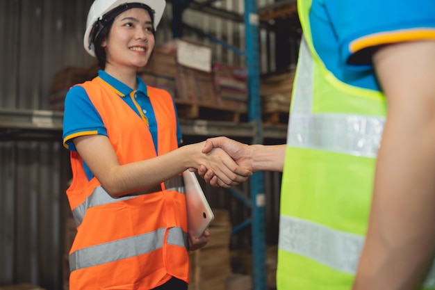 Il lavoratore asiatico del magazzino industriale nella stretta di mano della suite di sicurezza celebra l'impegno di successo o affare Catena di fornitura logistica e affari di magazzino Unità di lavoro di squadra sotto il concetto di vista