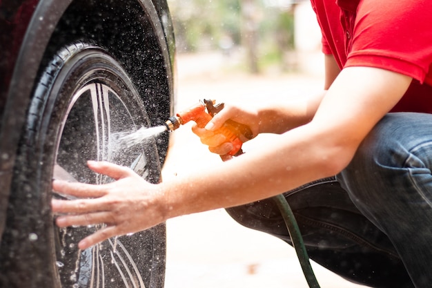 Il lavoratore dell&#39;uomo che lava i cerchi in lega dell&#39;auto nella cura dell&#39;auto.