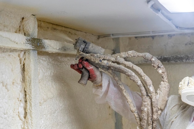 Il lavoratore in tuta protettiva isola le pareti con schiuma poliuretanica