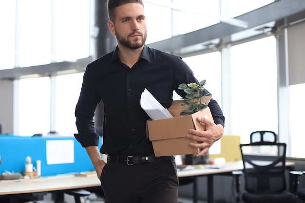 Il lavoratore licenziato triste sta portando con sé le sue forniture per ufficio dall'ufficio.