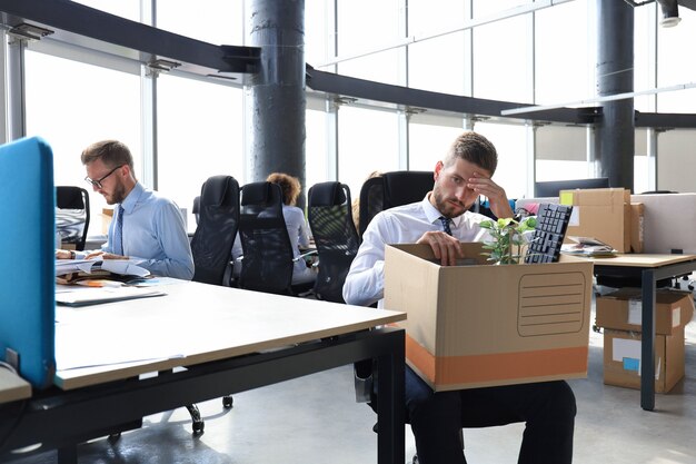 Il lavoratore licenziato triste sta portando con sé le sue forniture per ufficio dall'ufficio.