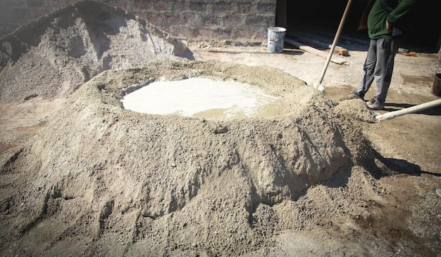 Il lavoratore prepara il calcestruzzo con la pala in cantiere