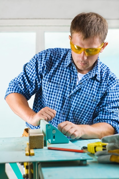 Il lavoratore regola la macchina per la lavorazione del legno