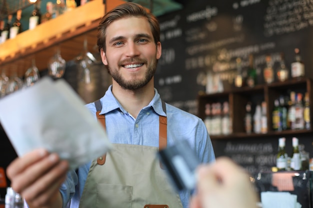 Il lavoratore sorridente prepara gli ordini alla panetteria.