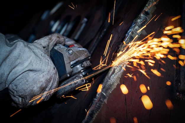 Il lavoratore sta macinando il metallo con una smerigliatrice angolare