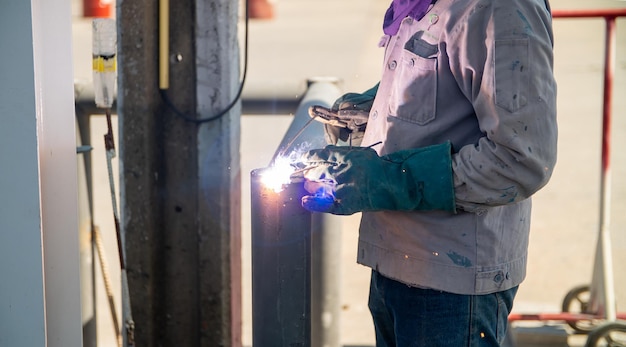 Il lavoratore sta saldando la struttura del telaio in acciaio in loco