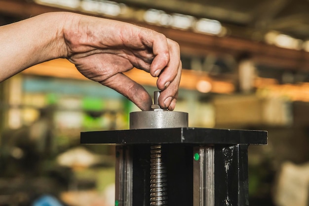 il lavoratore stringe un dado su una macchina con una mano sporca