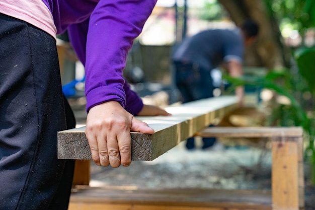 Il lavoratore strofina il grande piatto di legno lungo con la lucidatrice in giardino