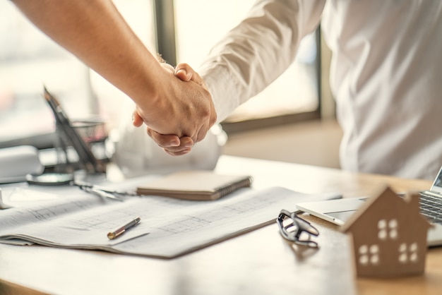 Il lavoro di squadra degli ufficiali è felice e si stringono la mano per celebrare con successo il completamento della pianificazione del lavoro sul progetto di costruzione di una casa