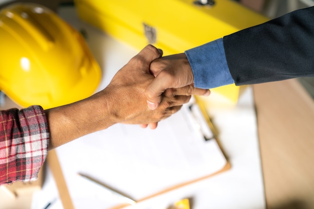 Il lavoro di squadra dell&#39;ufficiale è felice e stringe le mani per celebrare nella costruzione di edifici di successo