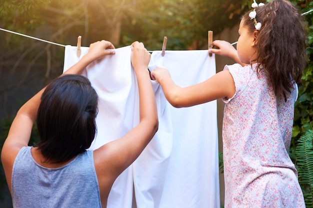 Il lavoro di squadra stende il bucato e una madre e un bambino fanno le faccende domestiche e sono impegnati con i vestiti Puliscono la famiglia e il retro di una bambina che aiuta insieme la mamma con i vestiti in fila nel cortile